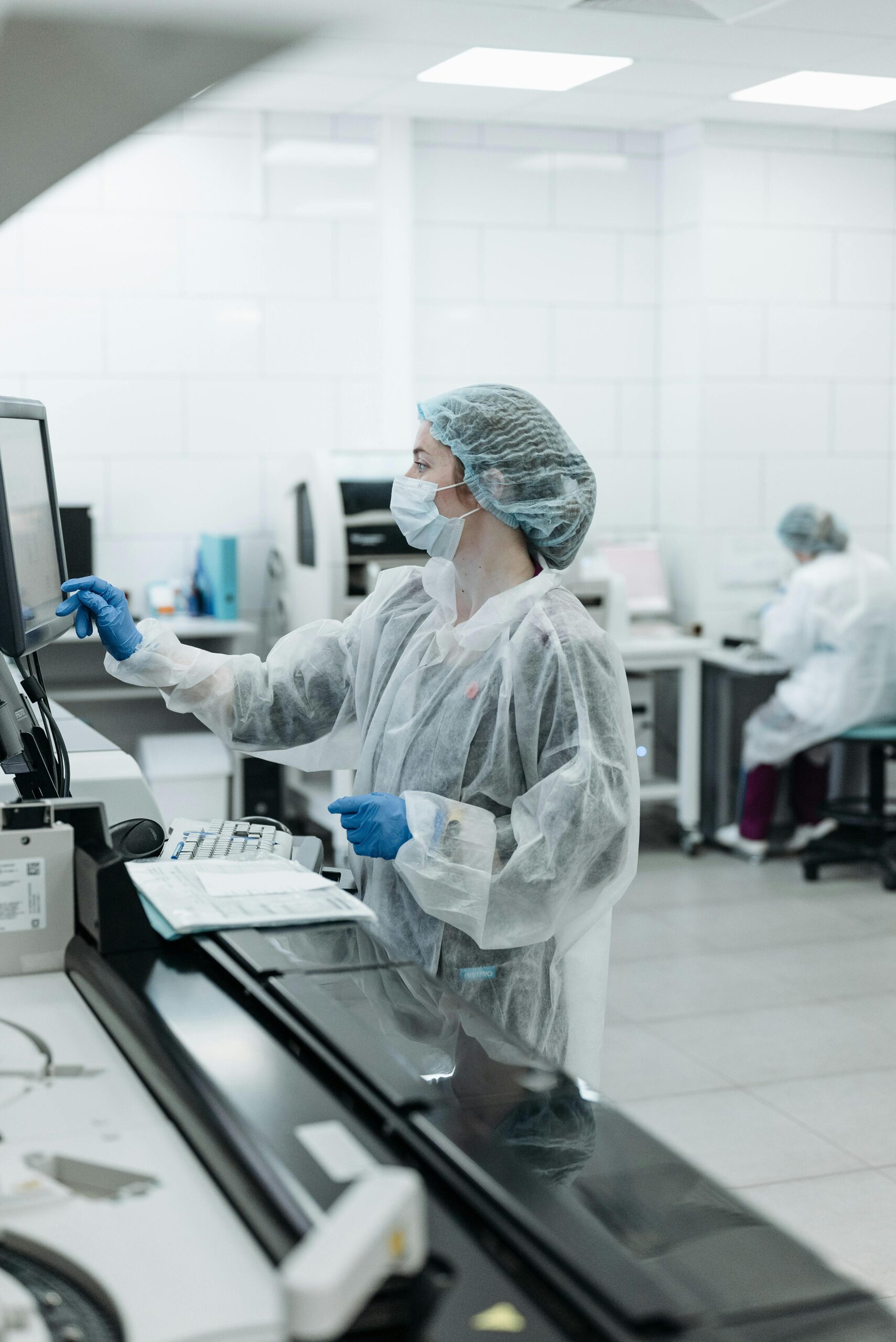 Female scientist in a sterile lab environment working on data analysis using a touchscreen.